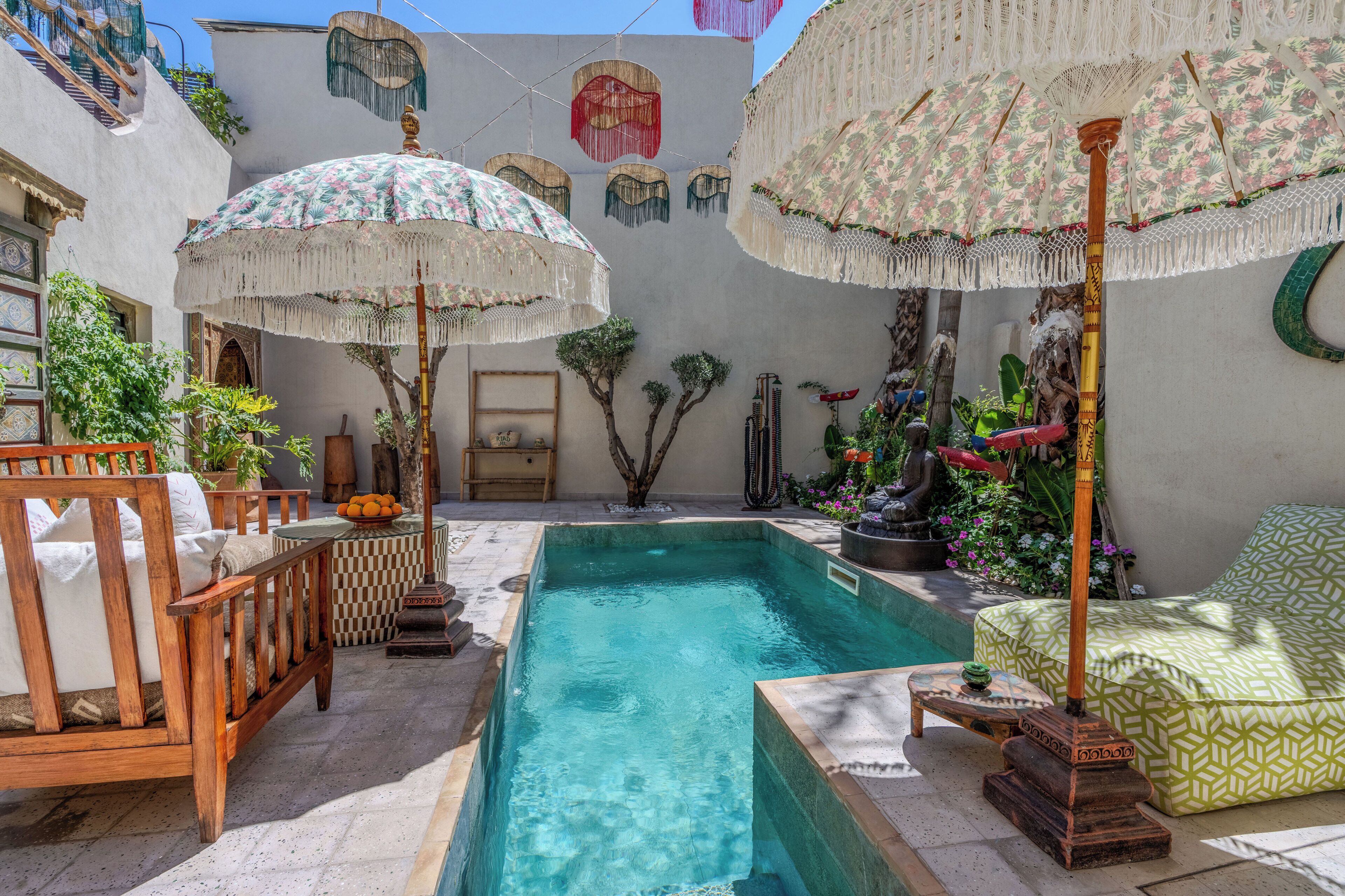 A pool area with a wooden chair, a small table, and a patterned sofa.