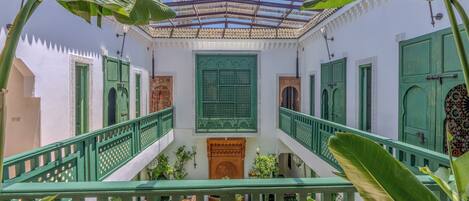 A courtyard with a central staircase, green railings, and white walls with decorative elements.