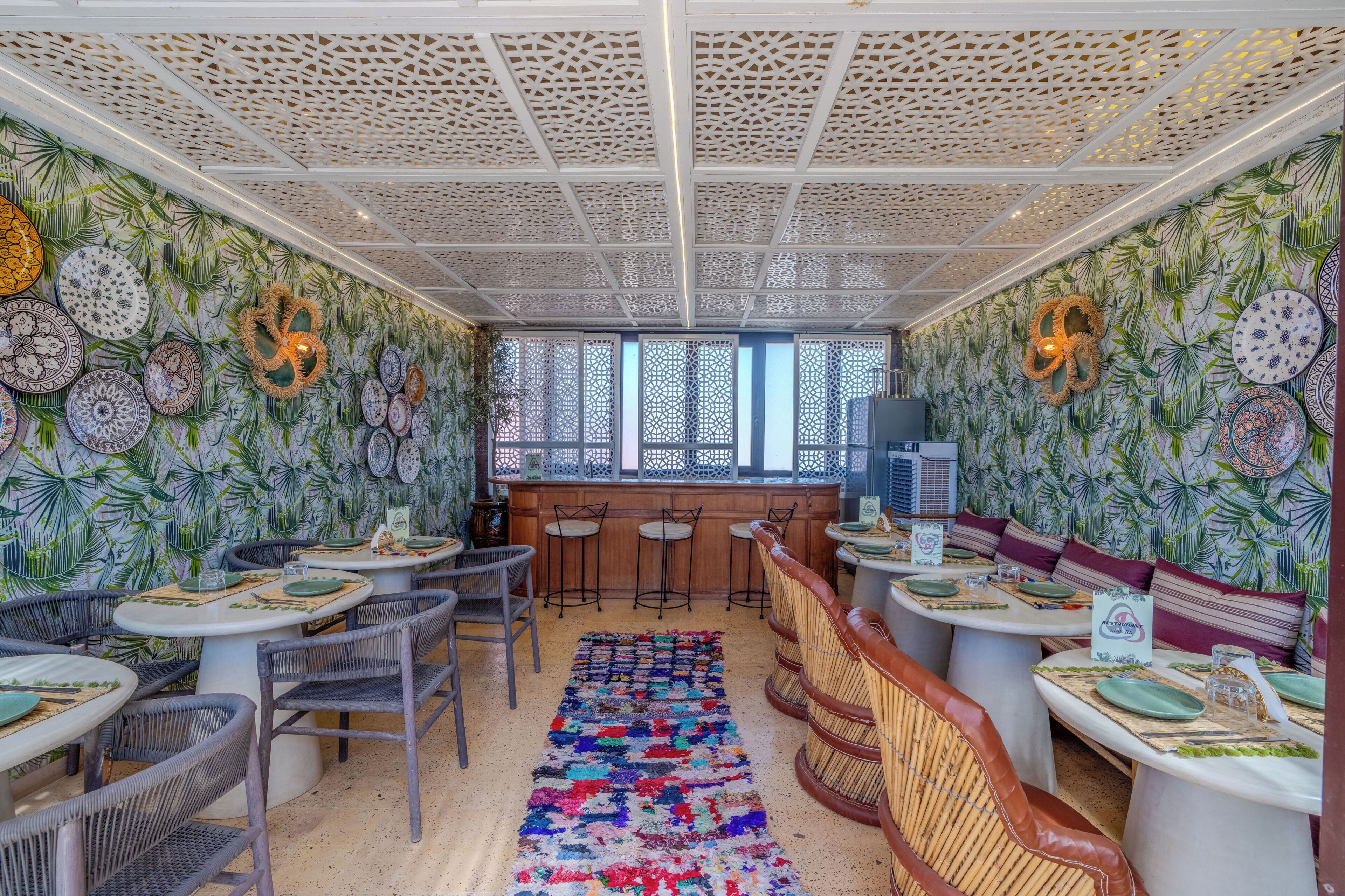 A restaurant with round tables, chairs, and a patterned rug.