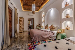 Una habitación con una cama, una mesita, un espejo y un techo decorativo.