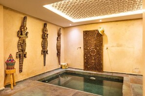 A spa area with a glass-enclosed hot tub, decorative wall carvings, and a textured ceiling. - Riad Jil & Spa Marrakech  (Marrakech)