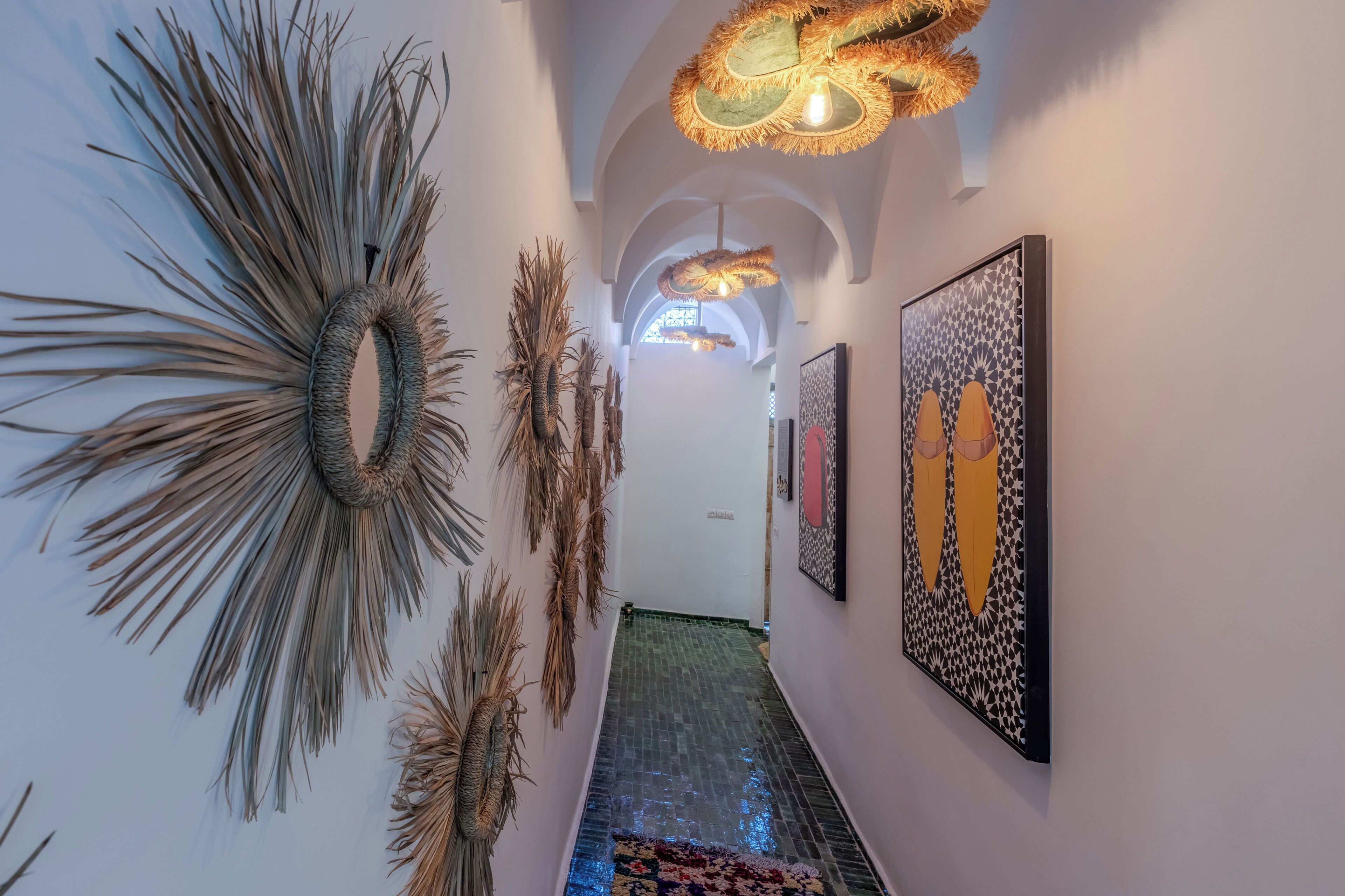 A hallway with a patterned floor, wall-mounted art, and a ceiling light fixture.