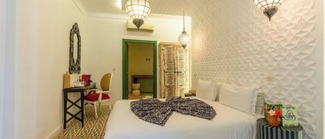 Una habitación de hotel con cama, escritorio, silla, lámpara y pared con diseño.
