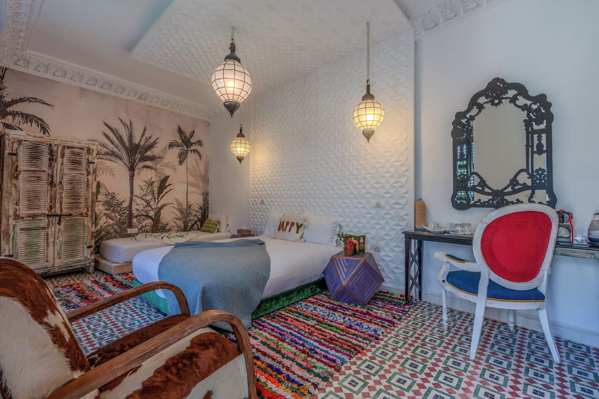 A room with a bed, a desk, a chair, a mirror, and a wall with a textured pattern.