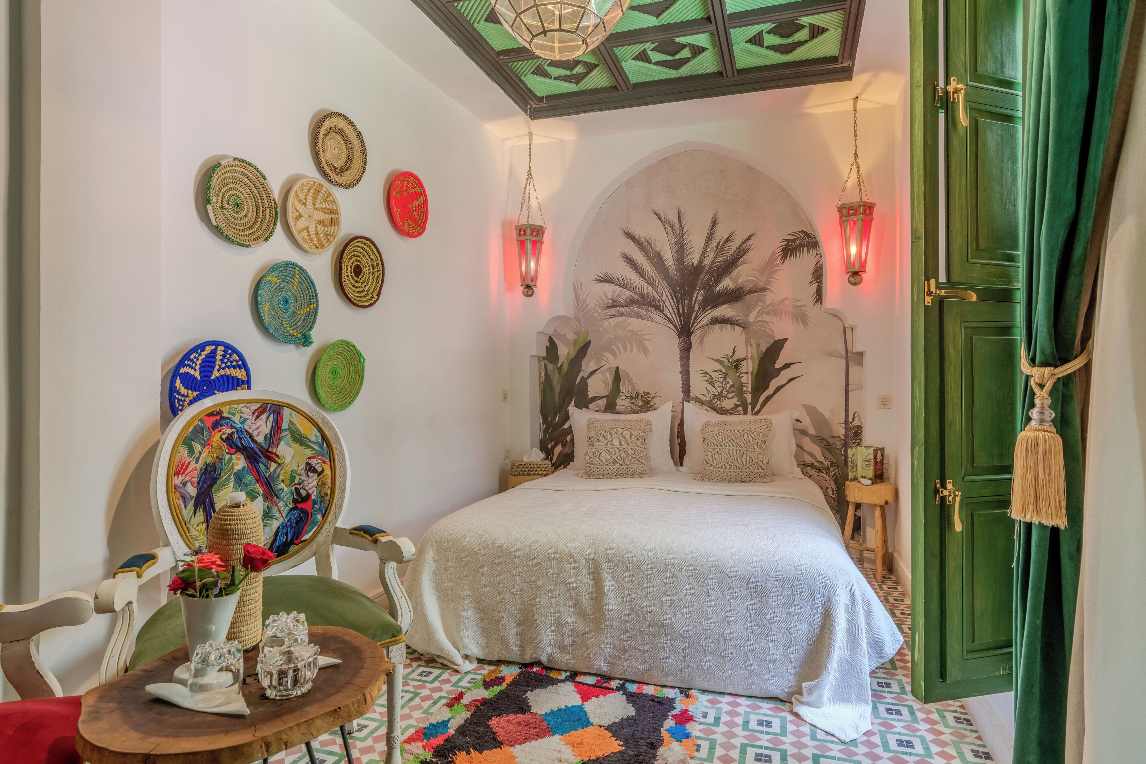 A bedroom with a bed, decorative plates, a painting, and a patterned rug.