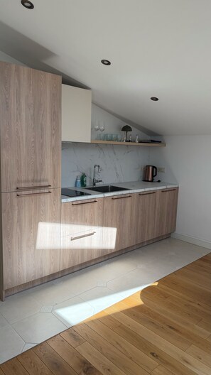 A modern kitchen with wooden cabinets, a marble backsplash, and a stainless steel sink. - Scandinavian Skylight Loft - Riga Quiet Center - Historic Building, AC (Rīga)