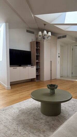 A modern living room with a flat-screen TV, built-in shelving, a chandelier, and a round table. - Scandinavian Skylight Loft - Riga Quiet Center - Historic Building, AC (Rīga)