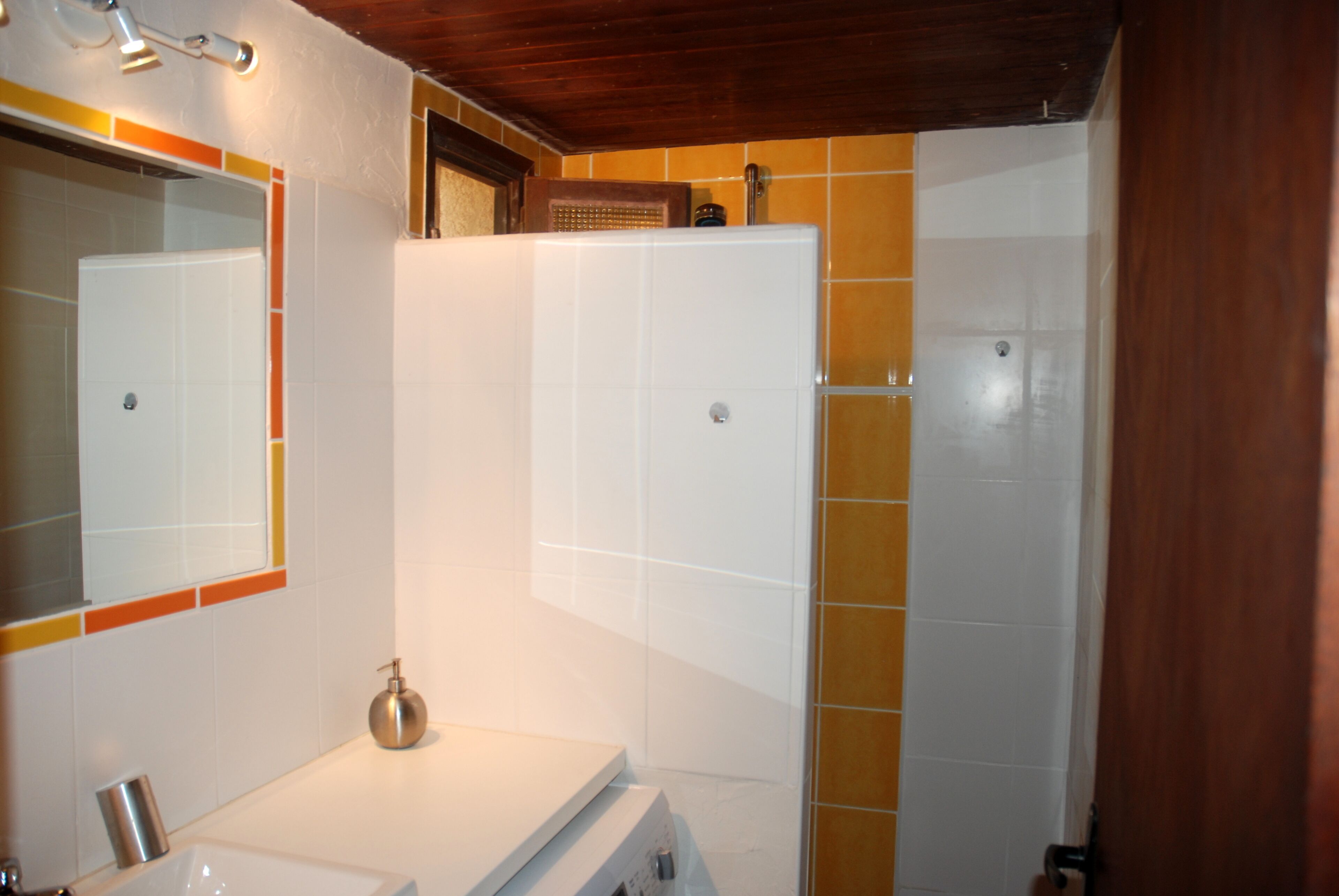 A bathroom with a white sink, mirror, and shower.