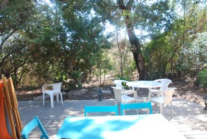 An outdoor patio with a wooden deck, white plastic chairs, and a table. - Air-conditioned villa; Santa Giulia Beach.  Hamlets of Pietragione (Porto-Vecchio)