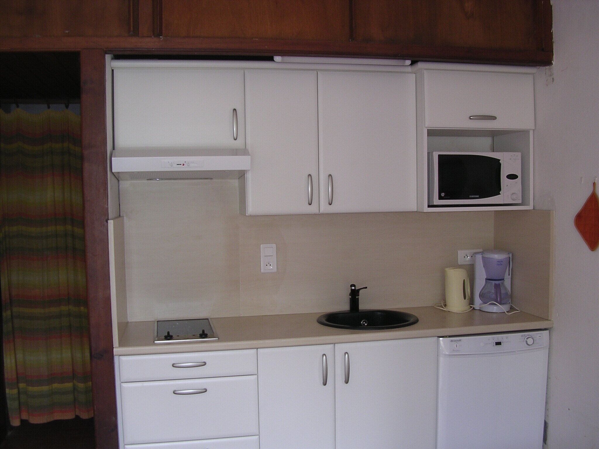 A small kitchenette with white cabinets, a microwave, a coffee maker, and a dishwasher.