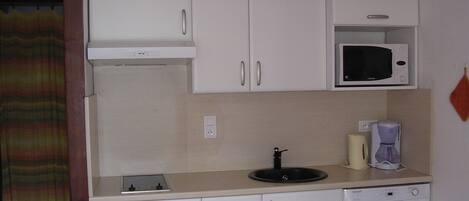 A small kitchenette with white cabinets, a microwave, a coffee maker, and a dishwasher.