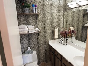 A bathroom with leopard print wallpaper, a white sink, and a mirror. There are shelves with towels and toiletries. - Houston TX - Houston Stadium - 2Be/2Ba Condo - WORLD CUP!!! (Houston)