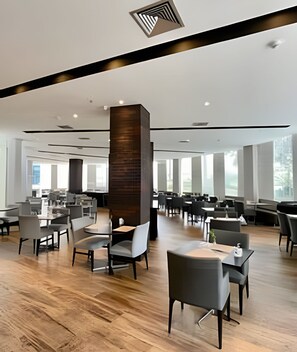 Un comedor amplio con mobiliario moderno y ventanas grandes.