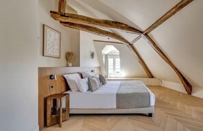 A bedroom with a sloped ceiling, a bed, a bedside table, and a window. - LIVE LIKE PARISIAN IN THE MOST FAMOUS NEIGHBOURHOOD-SAINT GERMAIN - RUE DAUPHINE (Paris)