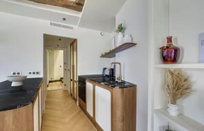 A modern kitchen with a black countertop, wooden cabinets, and a built-in stove. - LIVE LIKE PARISIAN IN THE MOST FAMOUS NEIGHBOURHOOD-SAINT GERMAIN - RUE DAUPHINE (Paris)