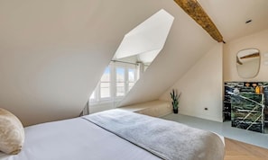 A bedroom with a sloped ceiling, a bed, a plant, and a bathroom with a marble countertop. - A REFINED PARISIAN ELEGANCE WITH CONTEMPORARY COMFORT-RUE DAUPHINE SAINT GERMAIN (Paris)