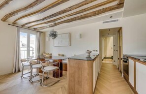 A modern kitchen with a wooden ceiling, a dining area with metal chairs, and a view through a window. - LIVE LIKE PARISIAN IN THE MOST FAMOUS NEIGHBOURHOOD-SAINT GERMAIN - RUE DAUPHINE (Paris)