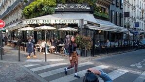 Un café con terraza, un paso de cebra y un hotel al fondo.