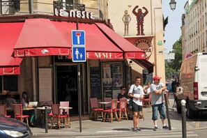 A café with outdoor seating, a blue handicap parking sign, and a chalkboard menu. - 3 bedroom apartment (Paris)