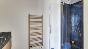 Un baño con ducha, toallero y calefactor en la pared.