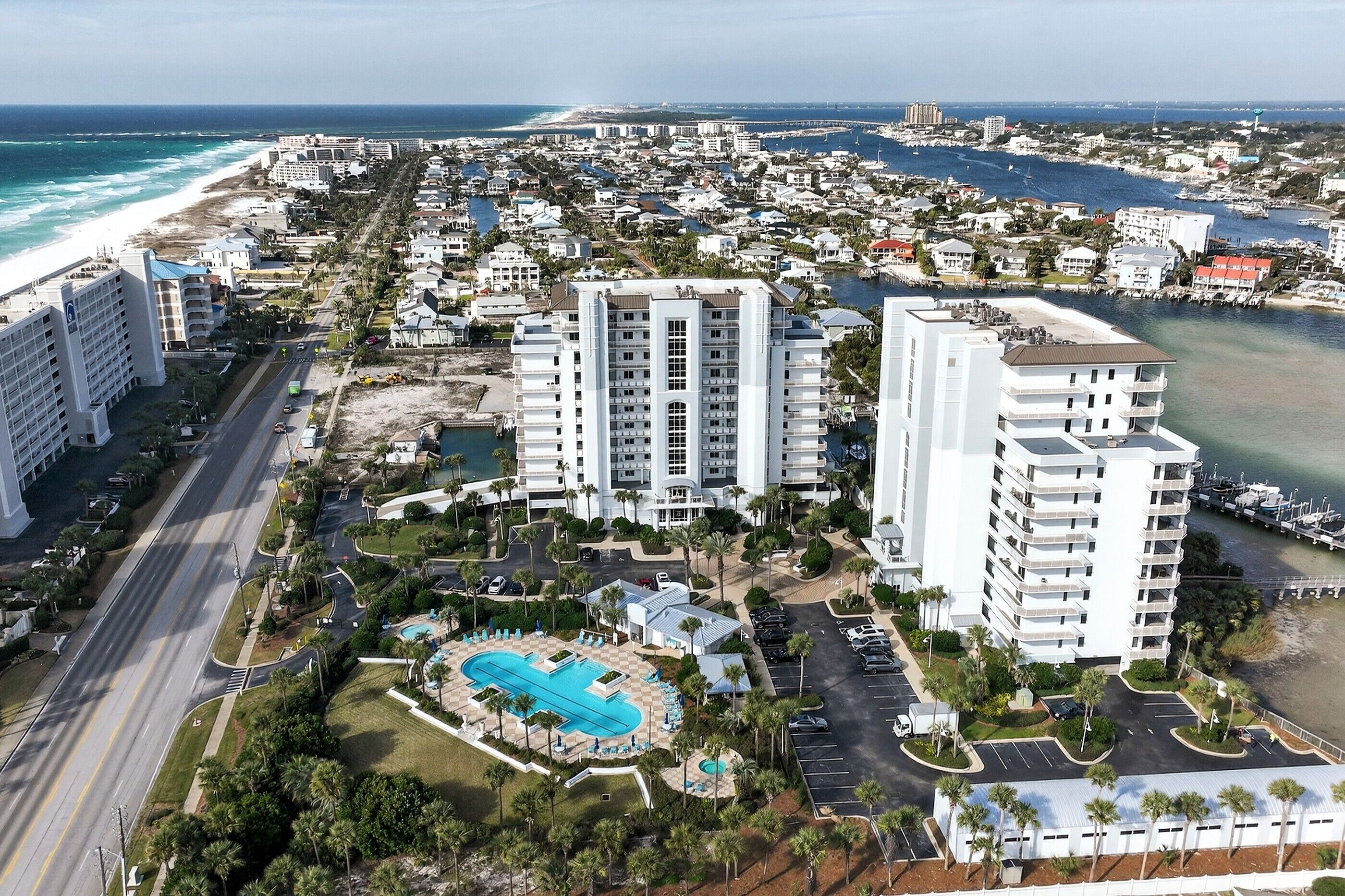 A coastal resort area with multiple high-rise buildings, a swimming pool, and a beachfront.
