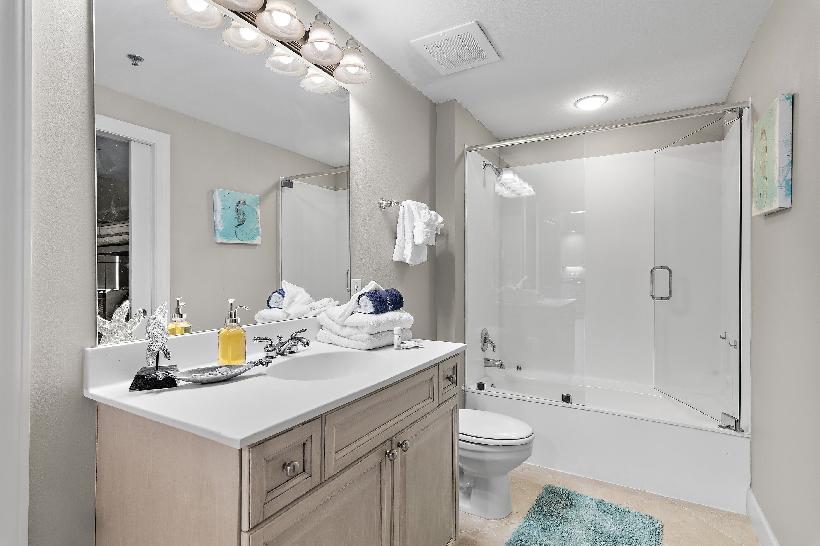 A modern bathroom with a glass shower enclosure, a white sink with a mirror, and a toilet.