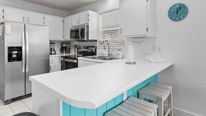 A modern kitchen with white cabinets, a stainless steel refrigerator, a microwave, and a sink. - Beachy 2BR Escape with Pool Views  | St. Martin Beachwalk Villa 314 (Destin)