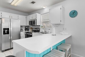 A modern kitchen with white cabinets, a stainless steel refrigerator, a microwave, and a sink. - Beachy 2BR Escape with Pool Views  | St. Martin Beachwalk Villa 314 (Destin)