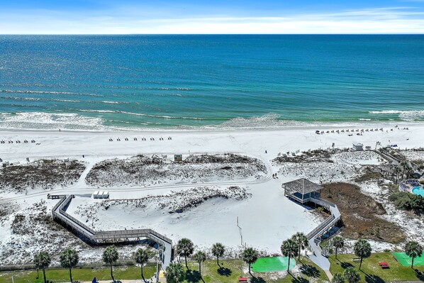 A beach resort with a large sandy area, a small water body, and a few structures including a building with a balcony. - Beachy 2BR Escape with Pool Views  | St. Martin Beachwalk Villa 314 (Destin)