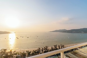 Vista costeira com praia, barcos e céu claro.
