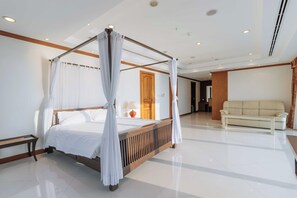 Uma cama de dossel com roupa de cama branca, uma cabeceira de madeira e um banquinho ao lado.