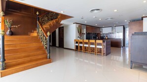 Un interior amplio con una escalera de madera, una zona de cocina y un comedor.