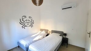 Ein Schlafzimmer mit zwei Betten, einer Wand-Klimaanlage, einer Pendelleuchte und einer Wandsticker.