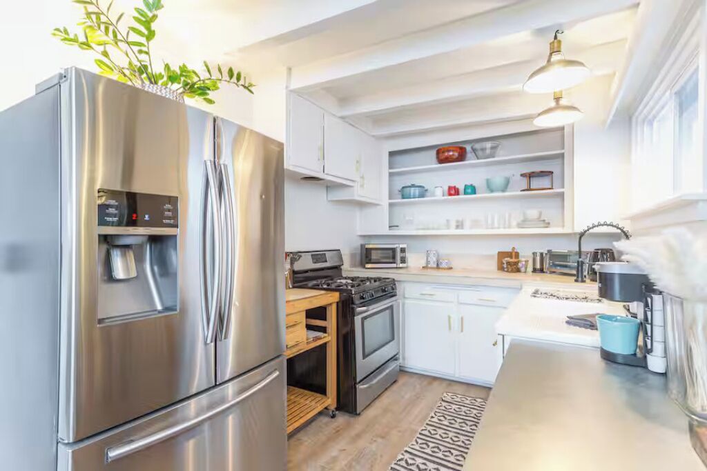 A modern kitchen with stainless steel appliances, white cabinetry, and a built-in oven.