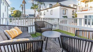 A balcony with outdoor furniture, a white fence, and a view of neighboring buildings. - Walk to Beach,Shops and Restaurants,Beach Cottage! (Newport Beach)