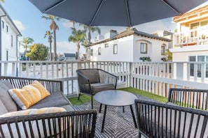 Ein Balkon mit Gartenmöbeln, einem weißen Zaun und Blick auf umliegende Gebäude.
