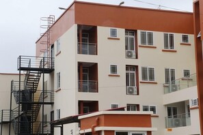 Un edificio de varios pisos con escalera de incendios, balcones y unidades de aire acondicionado.