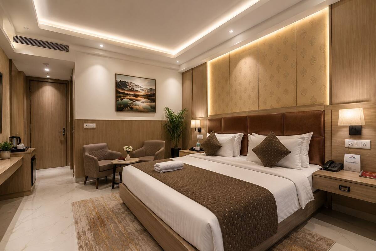 Una habitación de hotel moderna con una cama grande, un escritorio con una silla, una mesita con un florero y un cuadro en la pared.