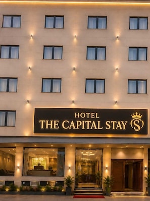A hotel with a sign reading 'THE CAPITAL STAY' and a crown symbol.
