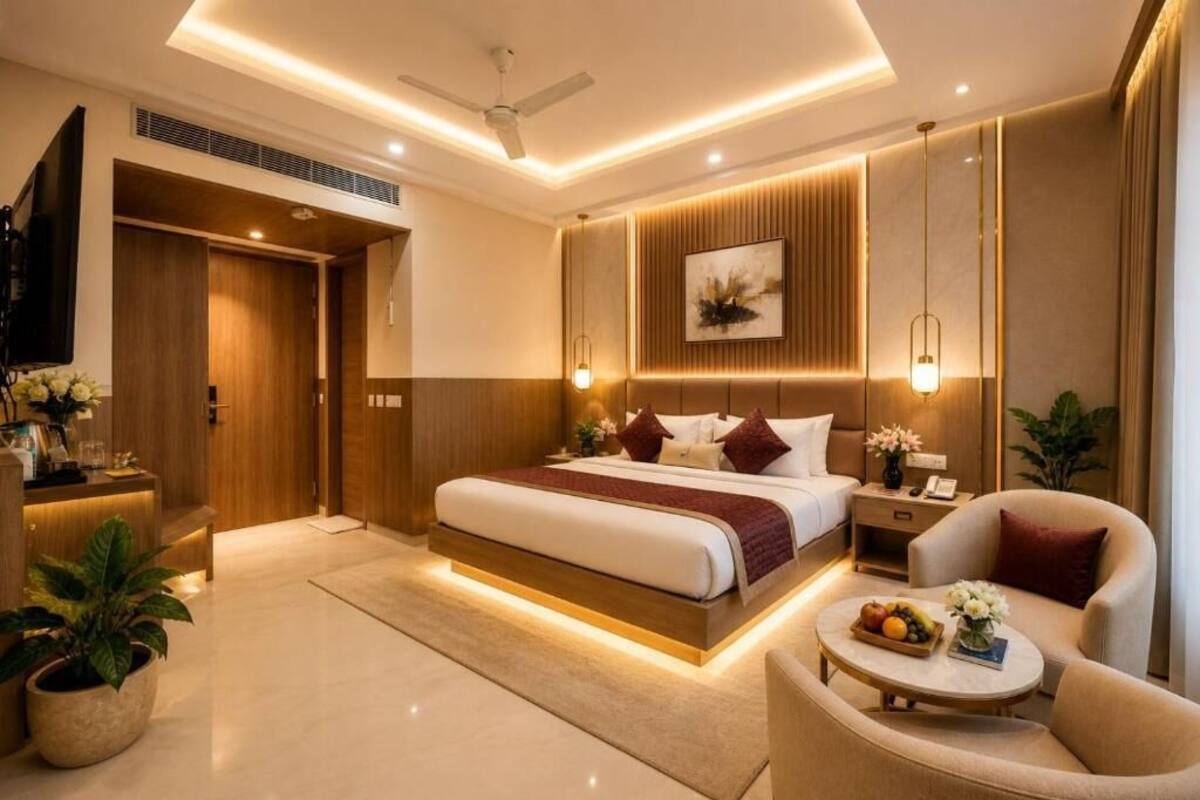 Una habitación de hotel moderna con una cama grande, mesitas de noche, un espacio de descanso y un televisor.
