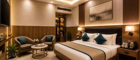 Una habitación de hotel moderna con una cama grande, dos sillones, una mesa de centro, televisión y ventilador de techo.