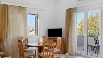 Ein Essbereich mit Tisch, Stühlen, einem Fernseher und Blick ins Freie.