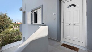 A white door with a small window above it and a doorbell on the wall. - Holiday Home 'La Casa Di Leone Casa Sorella' with Sea View, Wi-Fi and Air Conditioning (Agkisaras)