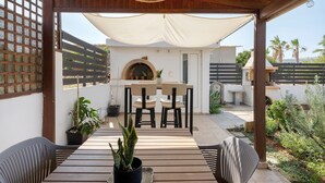 An outdoor patio with a table and chairs, a brick oven, and potted plants. - Holiday Home 'La Casa Di Leone Casa Sorella' with Sea View, Wi-Fi and Air Conditioning (Agkisaras)