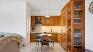 A compact kitchen with wooden cabinets, a dining table with chairs, and a built-in oven. - Holiday Home 'La Casa Di Leone Casa Sorella' with Sea View, Wi-Fi and Air Conditioning (Agkisaras)
