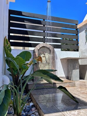 A fountain with water jets, a stone archway, and a wooden slatted structure. - Apartment 'La Casa Di Leone - Gio' with Shared Terrace, Wi-Fi and Air Conditioning (Agkisaras)