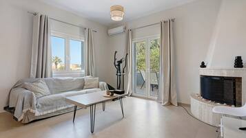 Ein modernes Wohnzimmer mit einer Couch, einem Tisch, einem Kamin und Blick durch Glastüren.