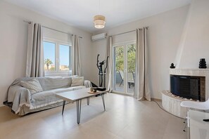 Un salon moderne avec un canapé, une table, une cheminée et une vue à travers les portes vitrées.