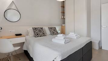 Een moderne slaapkamer met een bed, nachtkastje, bureau, stoel en een kledingkast.