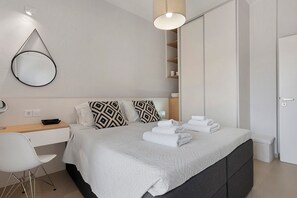 Une chambre à coucher moderne comprenant un lit, une table de chevet, un bureau, une chaise et une armoire.